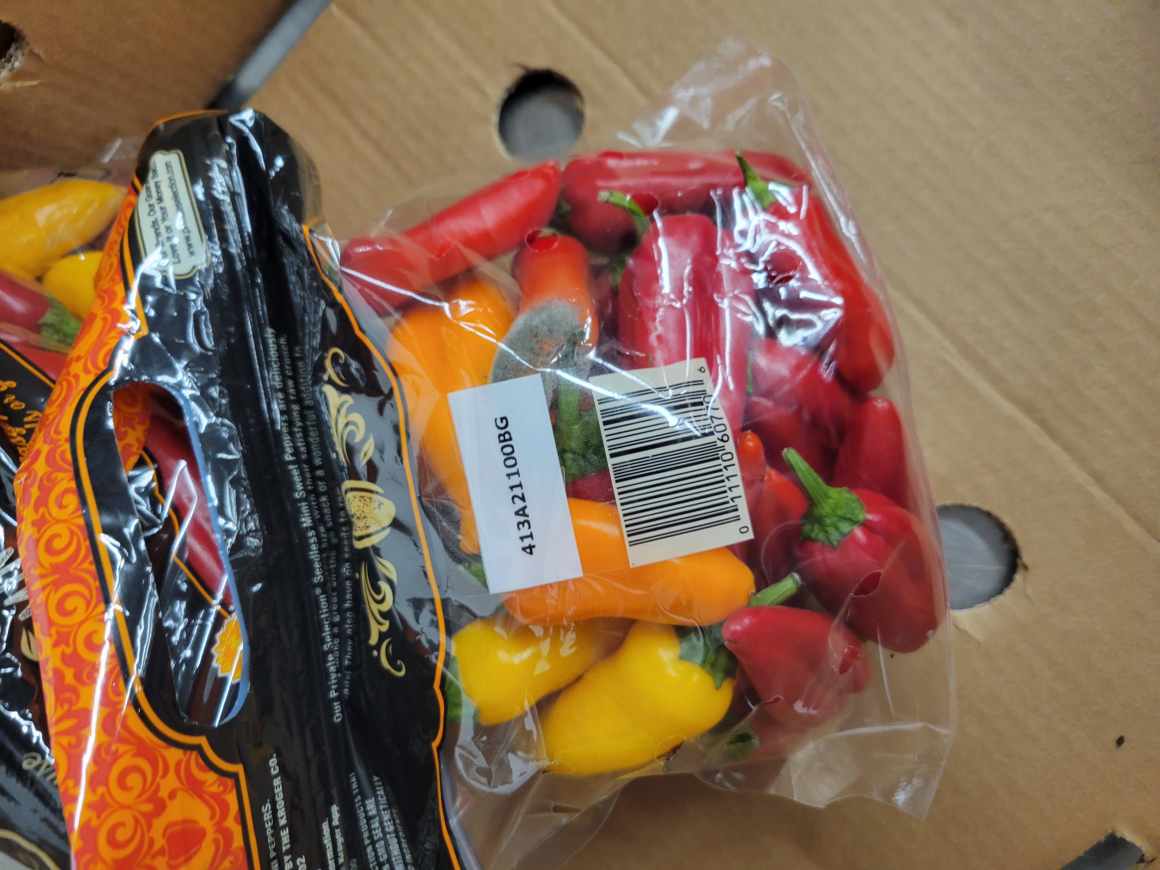 Bag of mini peppers on cardboard.